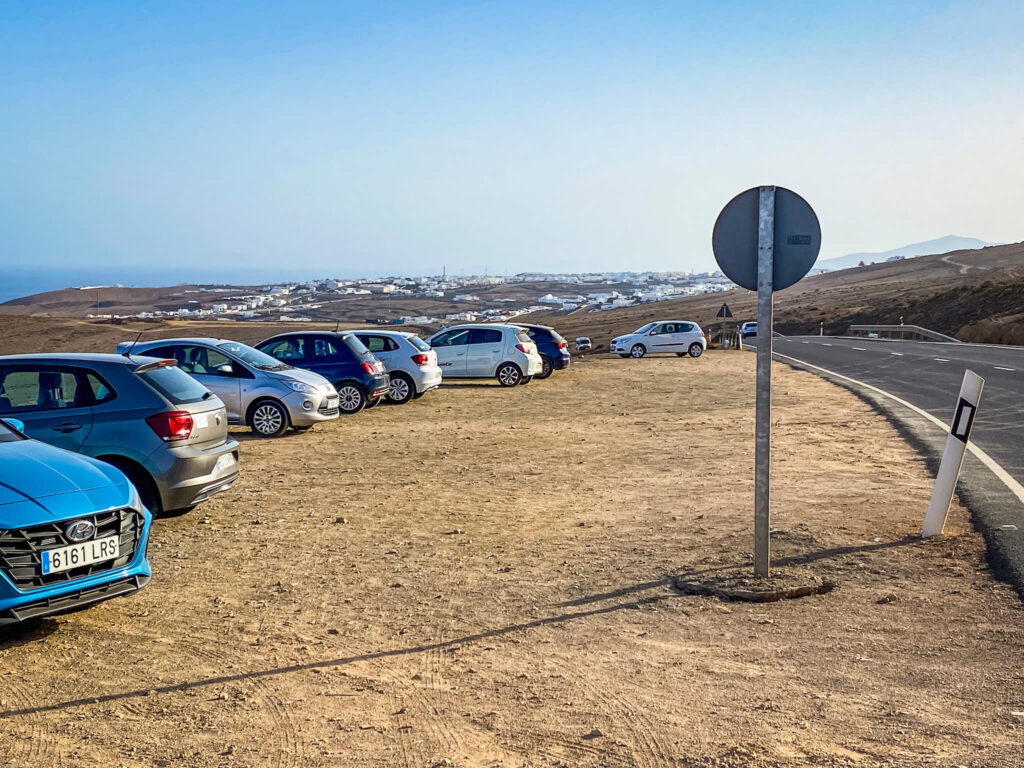 Parkplatz mit Autos und Ausblick über Dorf auf Lanzarote