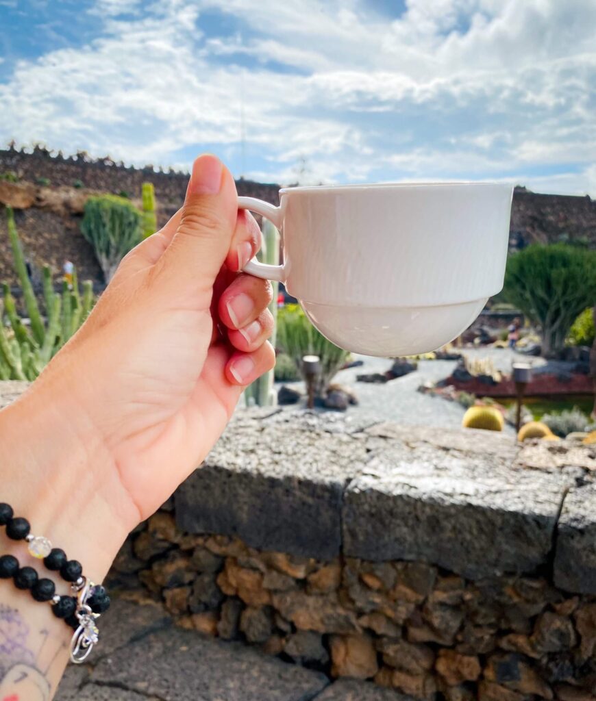 hochgehaltene Kaffeetasse im Kaktusgarten Lanzarote